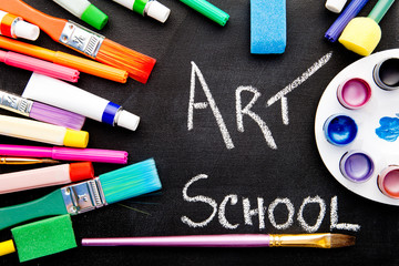 Fototapeta na wymiar Art School - handwritten on chalkboard surrounded by art equipment 