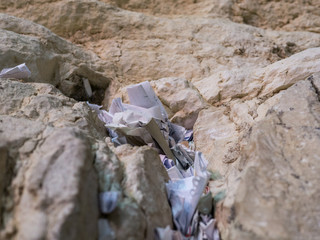 prayer paper notes inserted in a stone of the wailing wall - photographied from the bottom