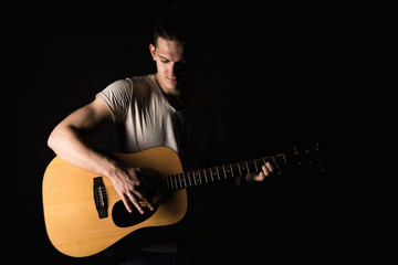 Guitarist, music. A young man plays an acoustic guitar on a black isolated background. Horizontal...