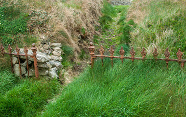 Wrought iron fence meets stone wall in rural Ireland