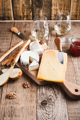 Cheese platter with wine, jam and walnuts on wooden board