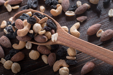 Dried fruits with nuts in a wooden spoon. Wooden background.