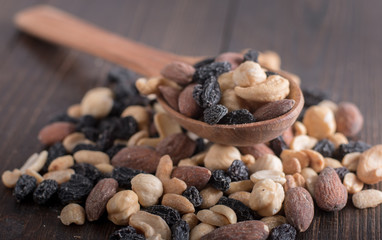 Dried fruits with nuts and raisins in a wooden spoon. Wooden background.