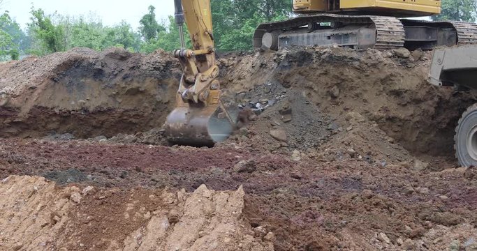 Heavy earth moving equipment excavating dirt pile