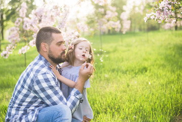 father and daughter blowing dandelion