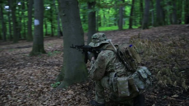 Guerilla partisan warrior aiming in forest ambush carrying his gun. Partisan war reconstruction. War battlefield maneuvers training.
