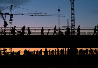 silhouettes of people crossing bridge with sunset sky background