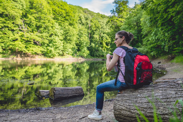 Fototapeta premium Woman sitting on a tree log by the lake