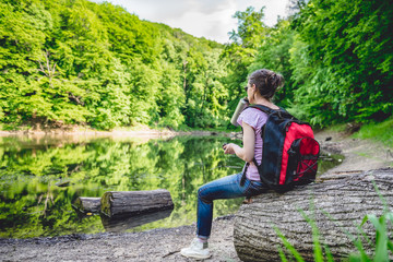 Fototapeta premium Woman sitting on a tree log by the lake