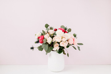 Beautiful flowers bouquet in flowerpot near pale pastel pink wall. Floral lifestyle composition.
