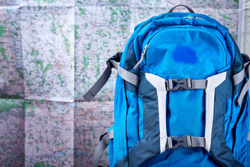 Tourist blue backpack against map background.