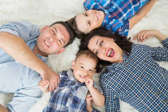 Happy family, mother, father and two sons having fun lying on the floor, upper view