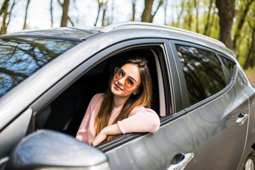 Smiling beautiful brunette woman driving a car on street