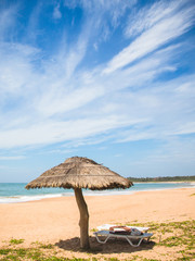 A straw umbrella and deckchair on kahandamodara beach, just outside of Tangalle, Sri Lanka.