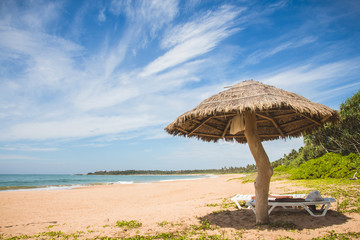 A straw umbrella and deckchair on kahandamodara beach, just outside of Tangalle, Sri Lanka.