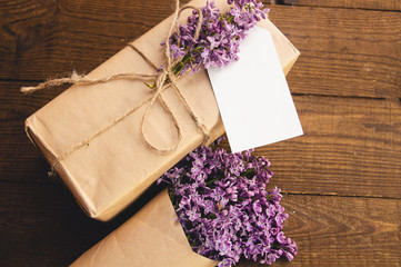 Bouquet of lilacs on a wooden table with a gift box