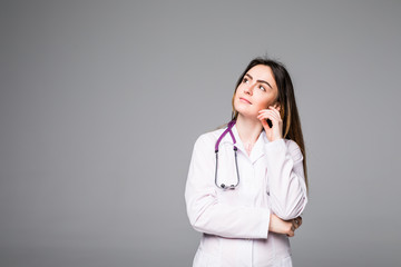 Friendly smiling young female doctor on grey background