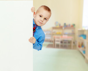 boy peeks out from behind the banner
