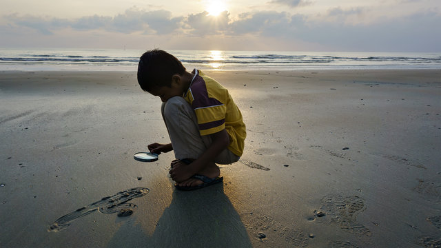 boy exploring nature by holding a magnifying glass