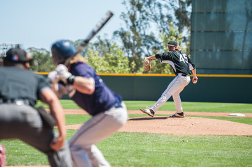 Baseball pitcher winding up to pitch to left handed batter. 