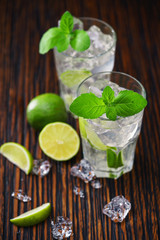 two glasses with  non-alcoholic mojito cocktail  served with limes and ice