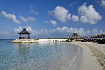 Clear warm water, blue sky, and a beach-side gazebo in the Caribbean