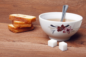 Black tea with sugar and cake with jam on wooden background