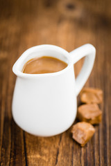 Portion of Caramel Sauce on wooden background (selective focus)