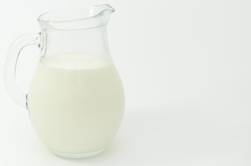 Fresh cow milk in a jar on a light background.