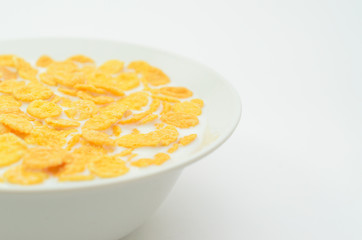 Cornflakes with milk on a spoon in a bowl on a light background.