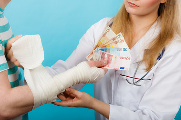 Female doctor bandaging male hand.