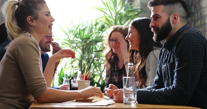 Young adult friends laughing and eating out together