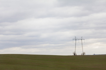 Fototapeta na wymiar Green field with double high-voltage tower - spring countryside in Russia