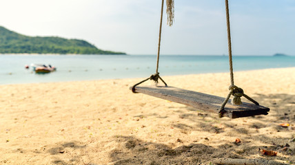 The beach swing is made of wood attached to the coconut trees No body