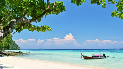 long tail boat  stop on the white sand beach on the island in the sunny day with green  tree white clound and blue sky