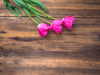 Pink tulips, floral arrangement on wooden background from old boards and a space for messages. Background for Mother's Day, 8 March and other greeting cards for lovely women. Soft focus, top view.