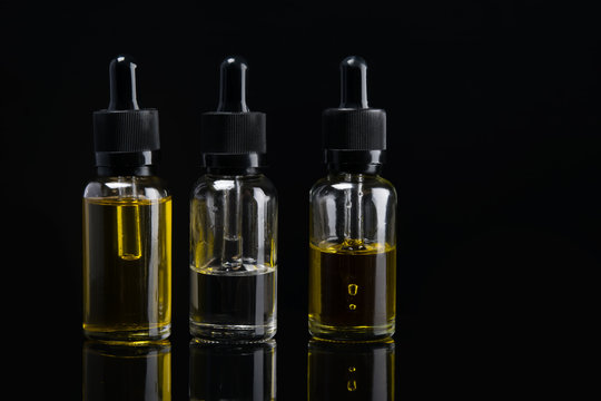three liquid bottles for e cigarette on black background