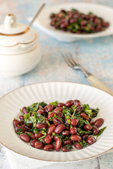 Salad of beans.   Salad of red beans with cilantro and garlic on white plates on an old wooden table.