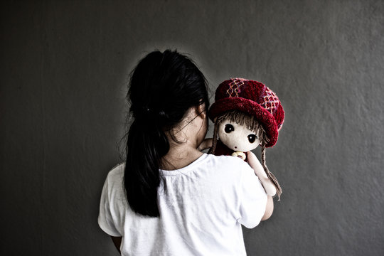 Asian lonely girl with doll sad gesture. Bullying and isolation concept.