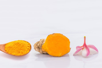 Soft blurred and soft focus of Turmeric powder on the wooden spoon, Zingiber, Turmeric root, Cassumunar ginger, Plumeria flower, with the white background. The local food and Thai herb in Thailand.