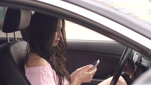 Young modern girl pays a purchase with a credit card through the phone while sitting in the car. 4K