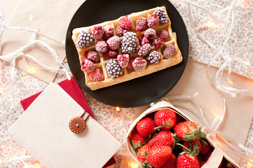 Waffle with raspberry and blackberry, books and fresh strawberry on table closeup. Top view. Good morning.