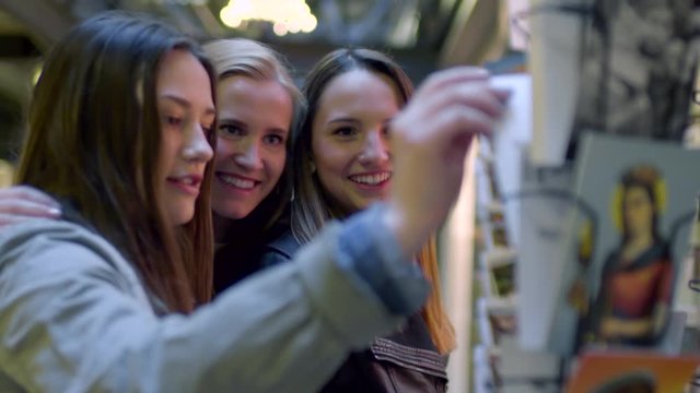Closeup Of Happy Teens On Vacation, They Look At Postcards On A Rack