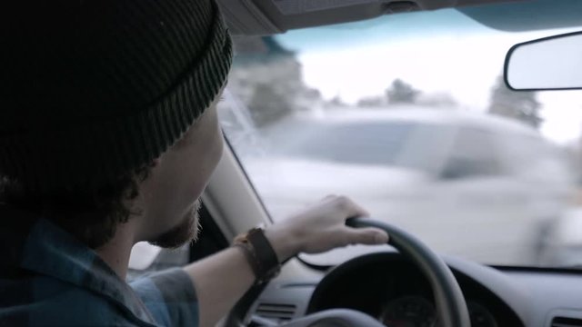 Young Man Drives A Car And Chats With Passenger, On Snowy Winter Day