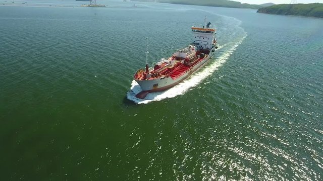 Modern red gas tanker trawler industrial steel ship in port of Vladivostok Primorsky Krai Russia Eastern Bosphorus. Russky Bridge sea ocean. Summer day blue water. Aerial drone flight over close to 4k