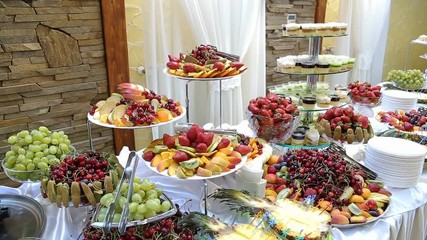 Tasty fruit - cherry strawberries kiwi pineapple peaches pears on buffet table.