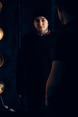 Fototapeta premium male hipsters in tattoos in black clothes, looks down on a dark background, the reflection