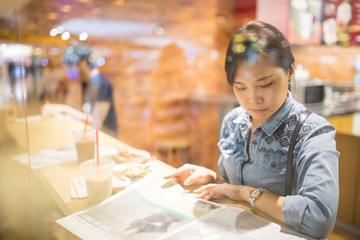 Asian woman reading magazine
