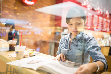Asian woman reading magazine