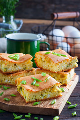 A jellied pie with green onions and eggs on a wooden board, selective focus